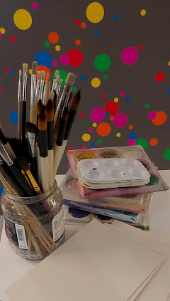 Siveltimiä, vesivärejä ja tyhjiä korttipohjia pöydällä.