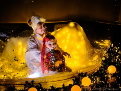 Kuvassa nainen ja tonttu istuvat vierekkäin ja taustalla on keltaista valoa.