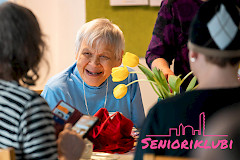 Henkilö istuu pöydän ääressä ja hymyilee.