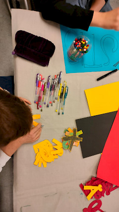 Erivärisiä papereita ja askartelevia henkilöitä