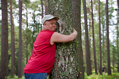 Nuori mies halaa puuta metsässä aurinkoisessa säässä