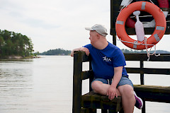 Nuori mies istuu laiturilla ja katsoo merelle. Takana pelastusrengas.