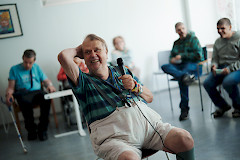 Leiriläinen istuu tuolilla ja nauraa iloisesti muiden katsoessa taaempaa.