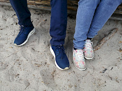 Kahdet jalat hiekalla. Molemmilla lenkkarit jalassa.