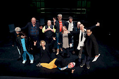 Ihmisiä seisoo ja istuu lattialla.