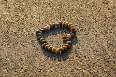 Kivistä muotoiltu sydän hiekalla.