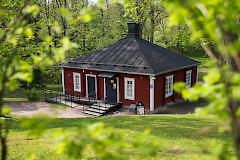 Punainen talo vehreän puiston ympäröimänä.