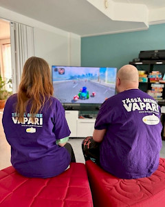 Kaksi henkilöä selin television ääressä.